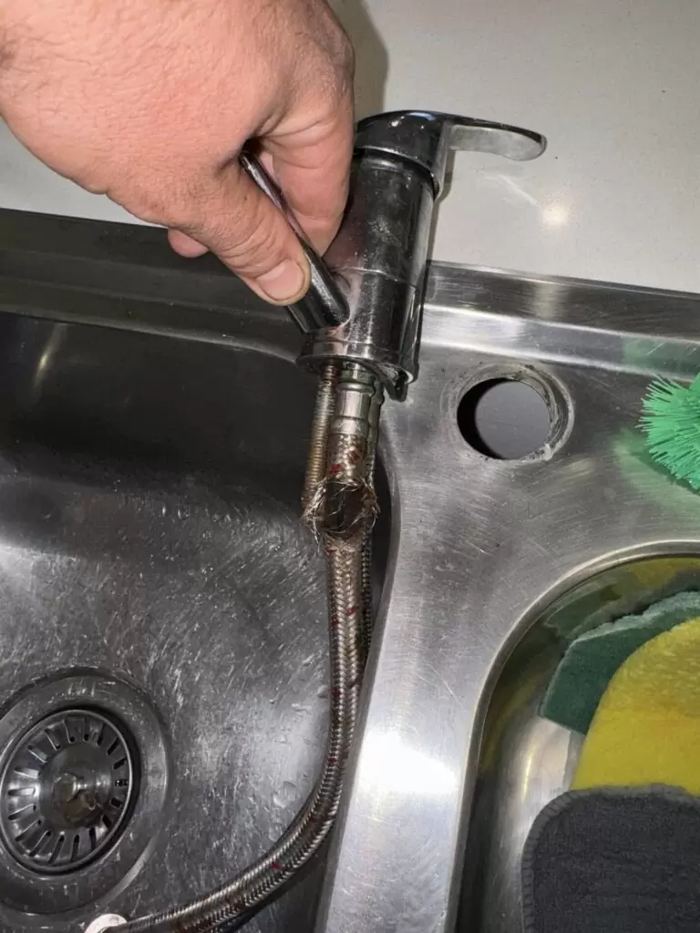 Burst flexi hose under kitchen sink in Pimpama Gold Coast showing split braided water supply line