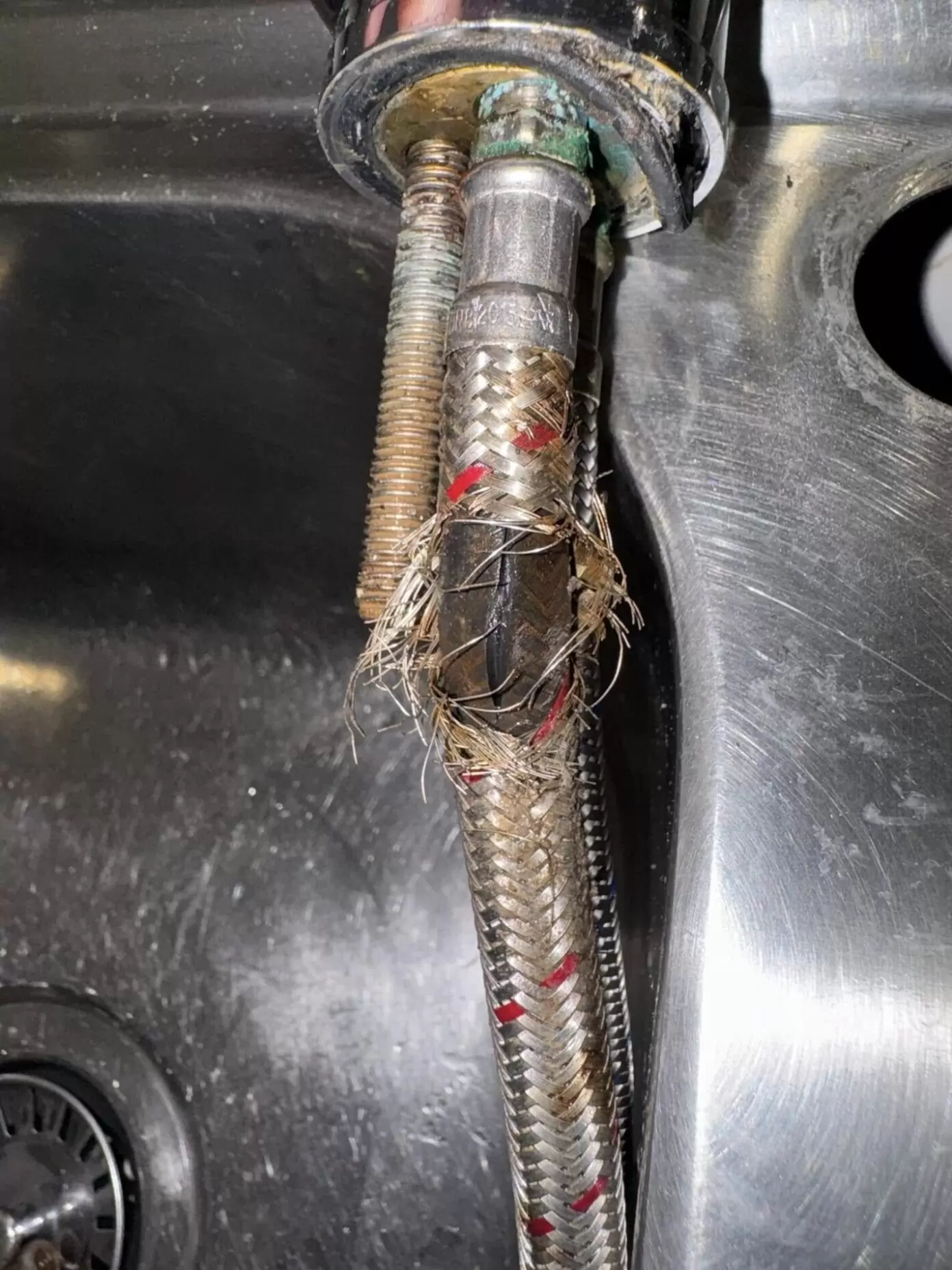 Close up of split braided flexi hose water supply line that burst in Pimpama kitchen sink