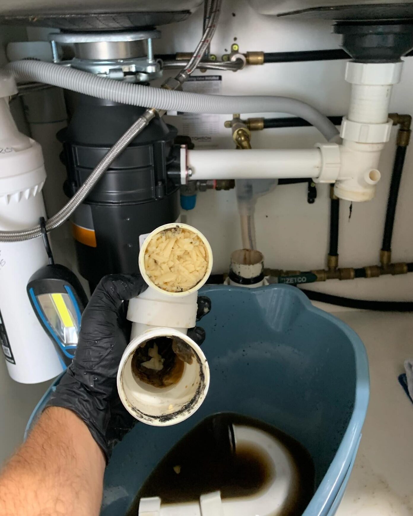 Gold Coast plumber clearing a blocked kitchen sink drain filled with food waste