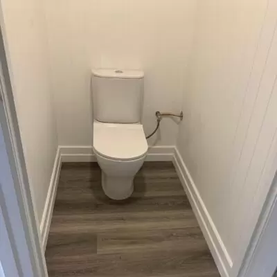 New toilet installation with vinyl flooring and white waterproof wall panels