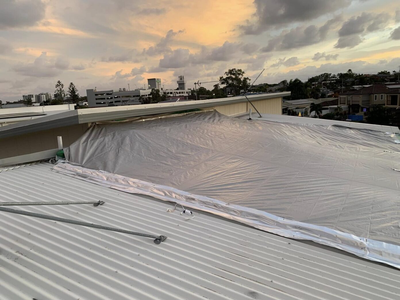 Leaking roof temporarily covered with tarp to prevent water ingress after storm damage