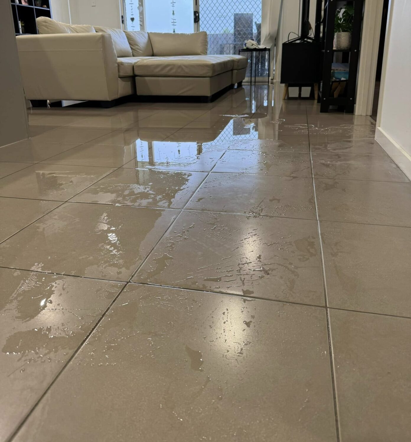Flooded tiled living area due to burst pipe or blocked drain causing water to pool indoors