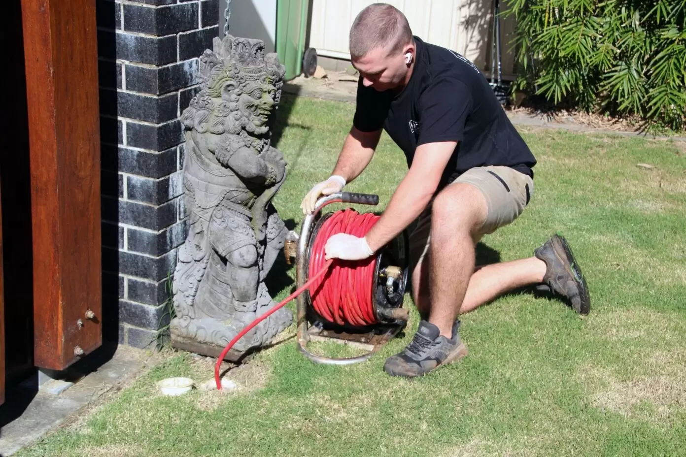 Gold Coast plumber using high-pressure jetting equipment to clear a blocked outdoor drain