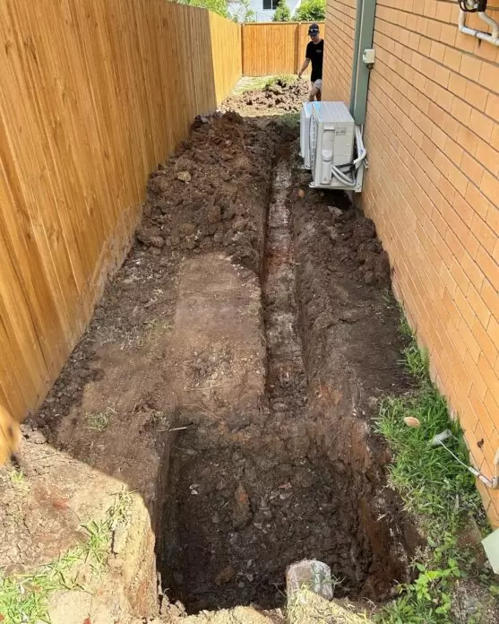 Stormwater drainage trench dug along fence line during residential stormwater upgrade in Brisbane