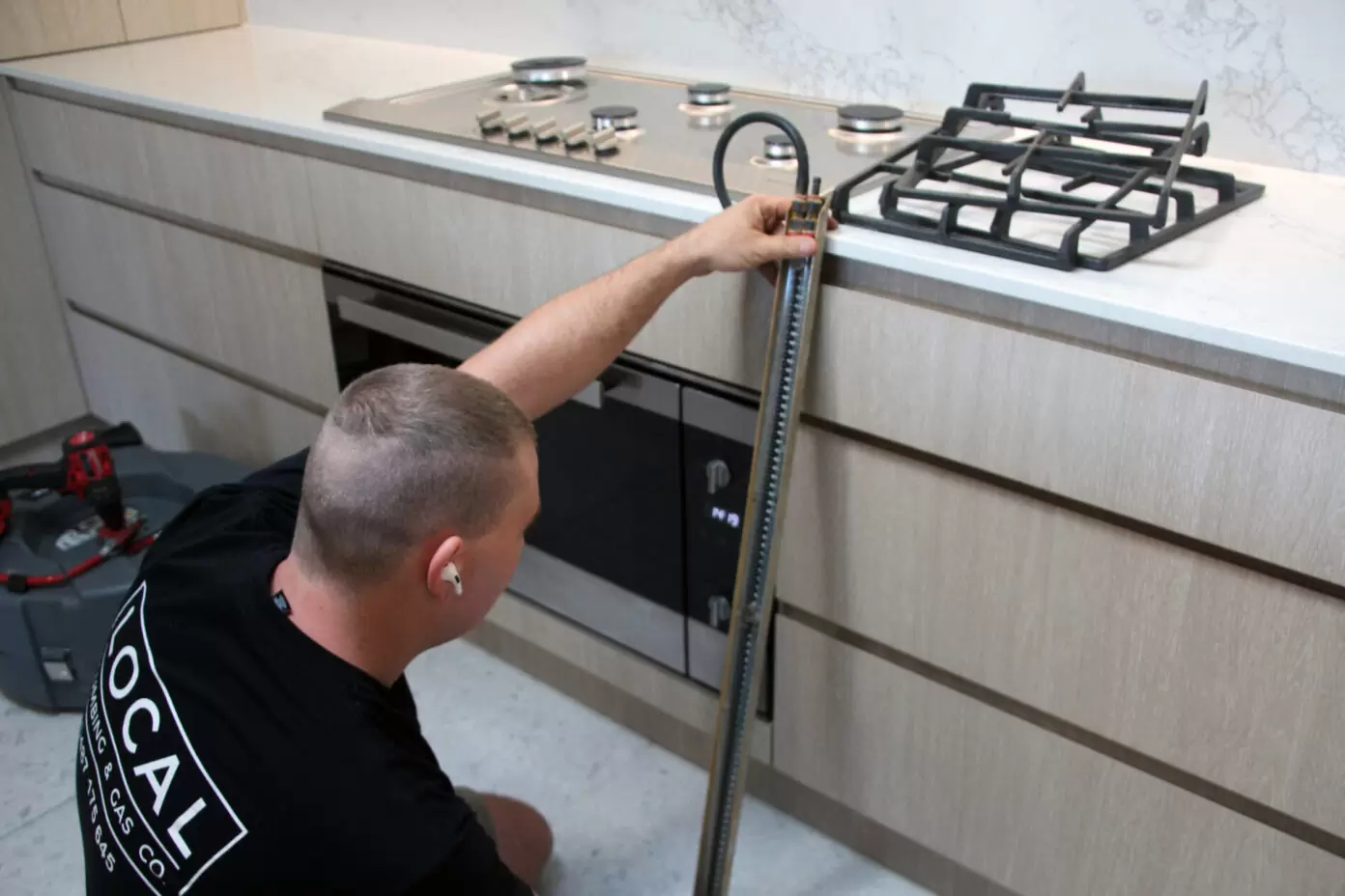 Licensed gas fitter testing appliance gas pressure during a kitchen installation on the Gold Coast
