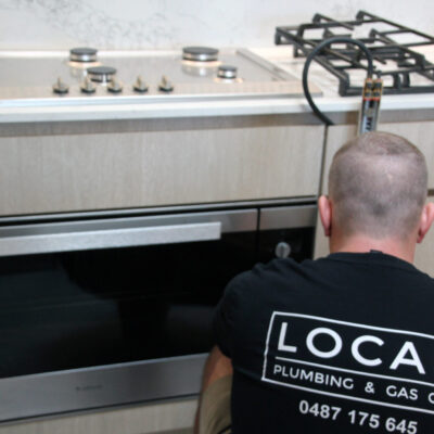 Local Plumbing & Gas Co. technician testing gas oven connection.
