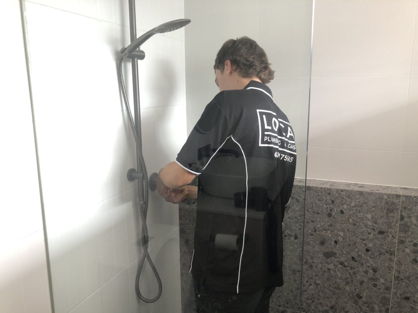 Licensed plumber inspecting shower plumbing for water leaks in Gold Coast bathroom