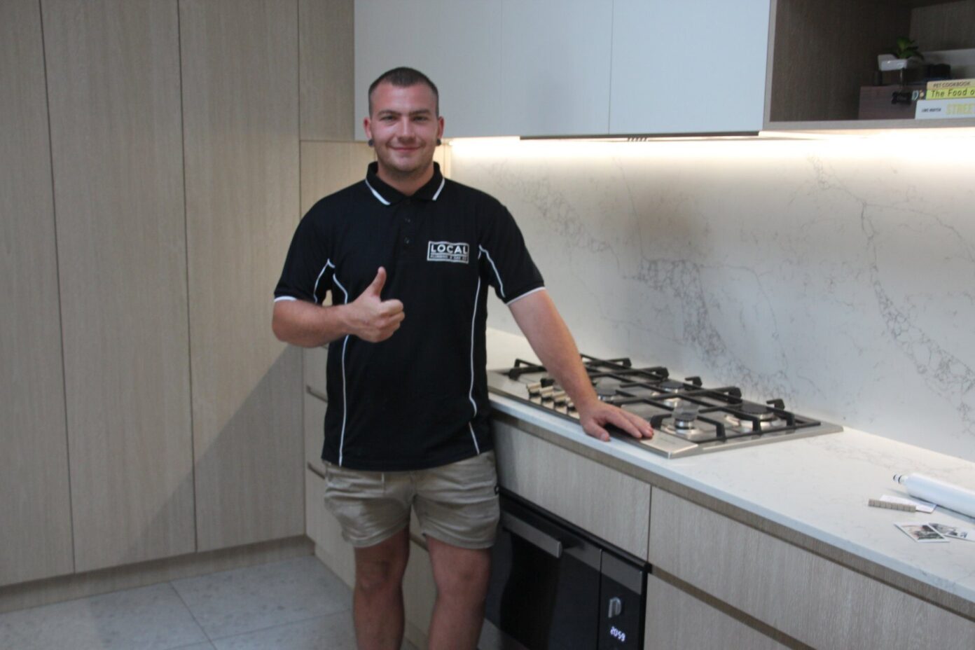 Licensed Plumber Gas Fitting Specialist in Gold Coast giving a thumbs up after installing a gas cooktop in a modern kitchen
