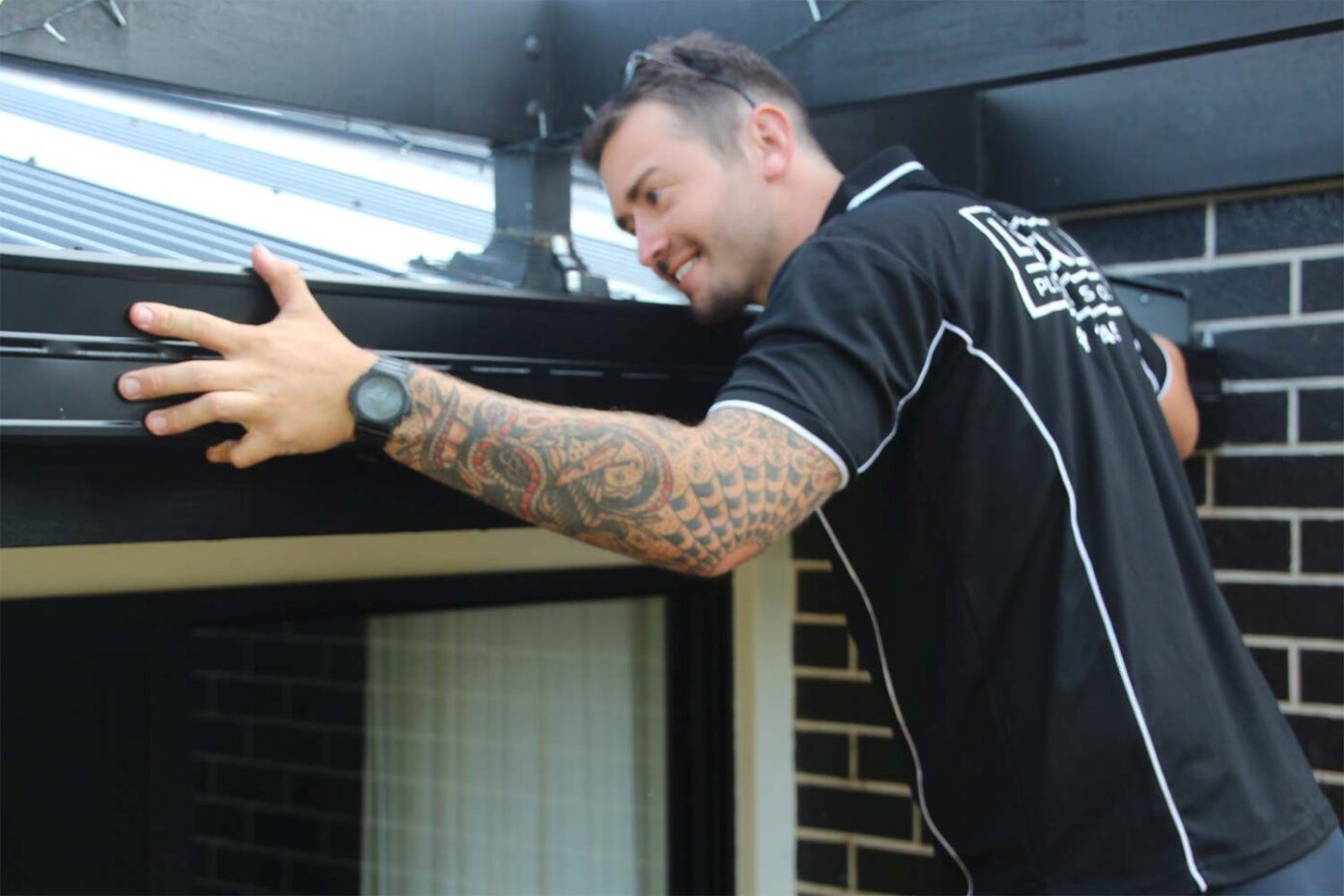 Local Gold Coast plumber inspecting and repairing a modern gutter system on a residential home.