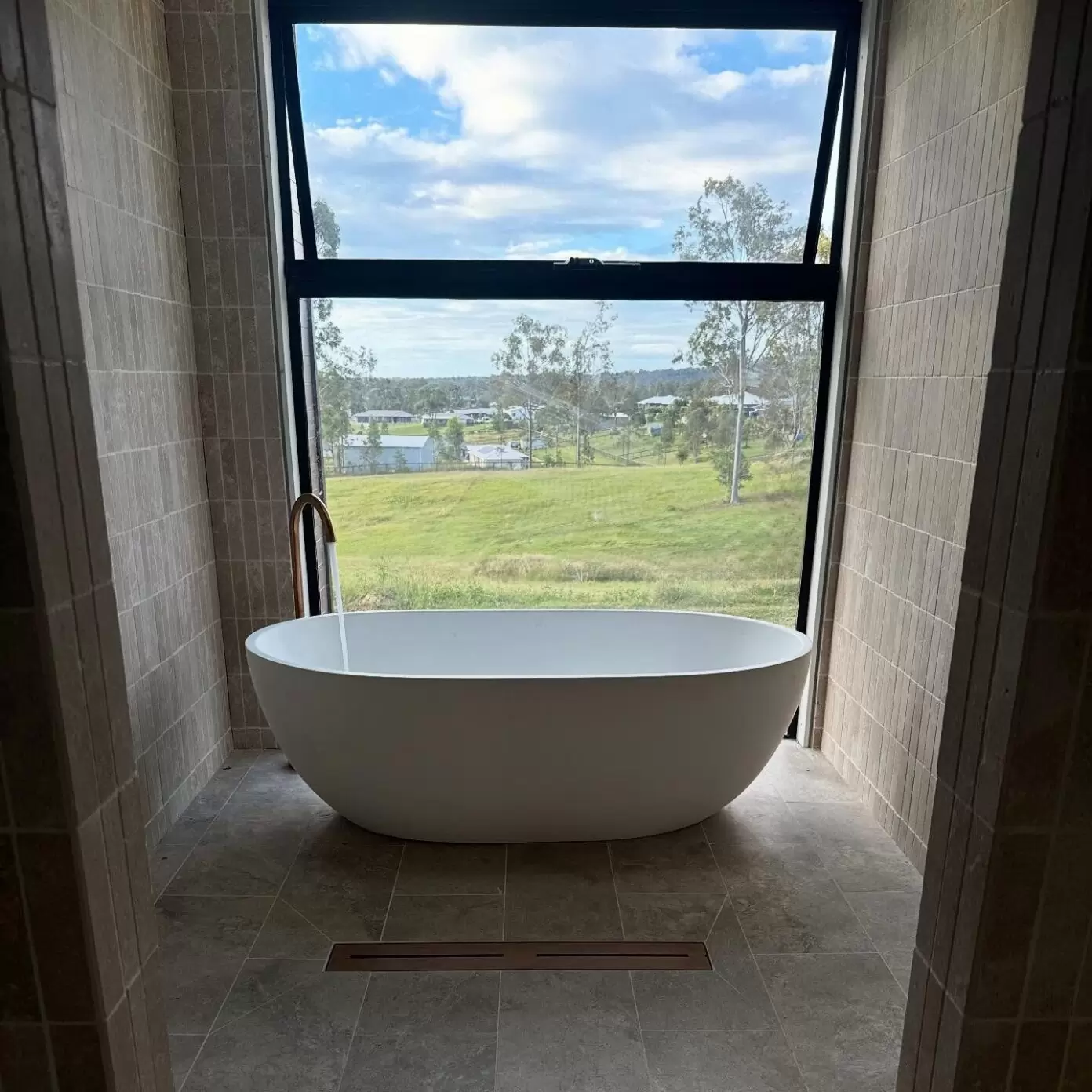 Freestanding bath with floor-mounted mixer in a luxury bathroom overlooking green fields in Jimboomba