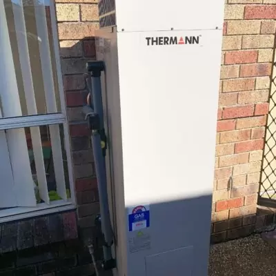 Thermann gas hot water system installed beside brick home.