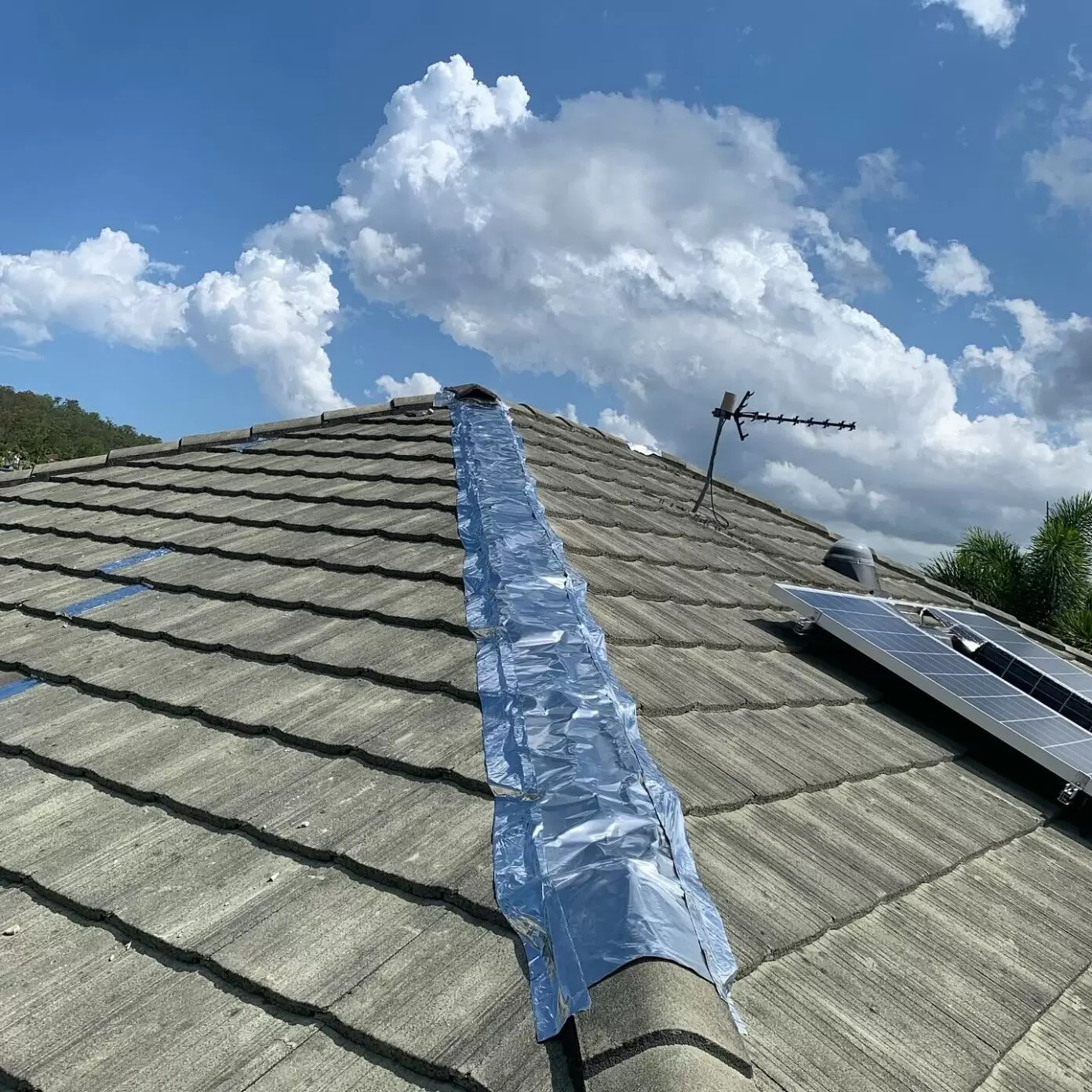 Close-up of a tiled roof with silver flashing tape applied along the ridge cap for waterproofing repairs on a residential home in the Gold Coast.