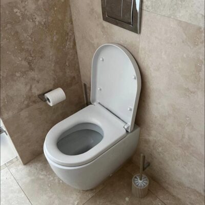 Wall-hung dual flush toilet with modern concealed cistern and travertine tiles on the Gold Coast