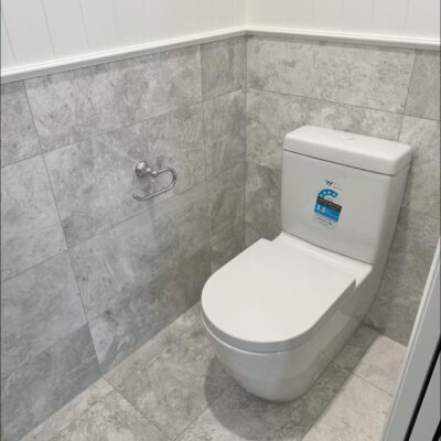 Close-coupled toilet installation in Runaway Bay with tiled feature wall and grey stone floor