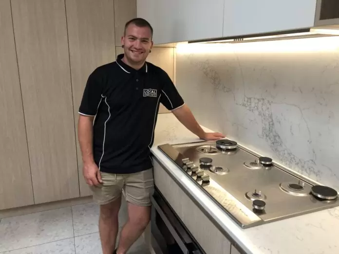 Licensed gas plumber from Local Plumbing & Gas Co. standing beside a newly installed gas cooktop on the Gold Coast