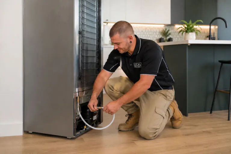 Local Plumbing & Gas Co. plumber connecting a water line to a plumbed fridge on the Gold Coast