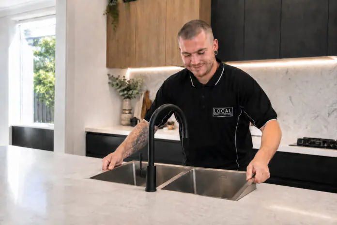 Local Plumbing & Gas Co. plumber installing a double-bowl kitchen sink on the Gold Coast