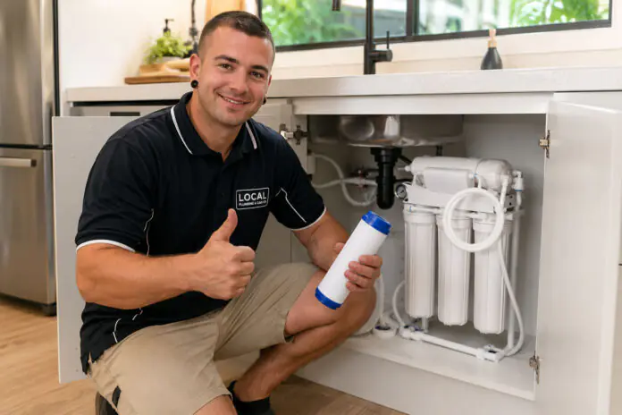 Local Plumbing & Gas Co. plumber beside an installed under-sink reverse osmosis water filter system