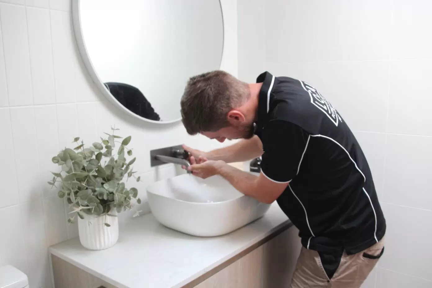 Gold Coast plumber repairing bathroom basin tap during maintenance plumbing work