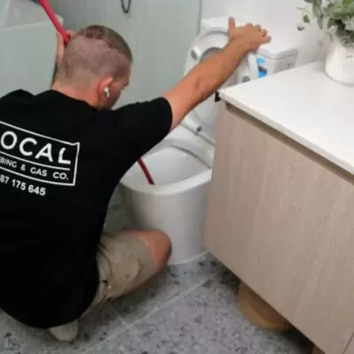 Plumber clearing a blocked toilet on the Gold Coast using a plunger