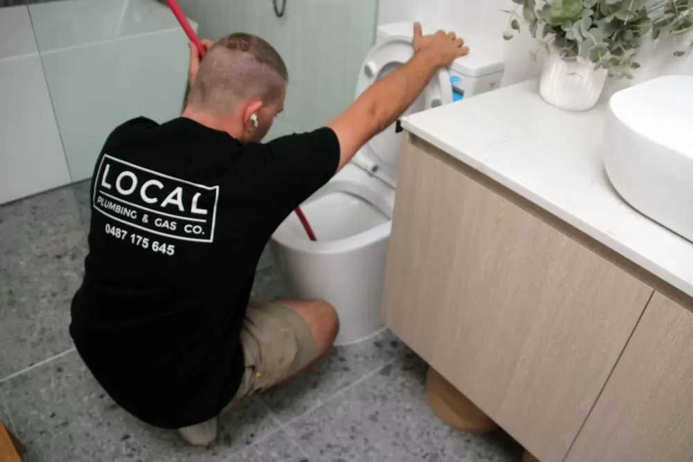 Plumber clearing a blocked toilet on the Gold Coast using a plunger