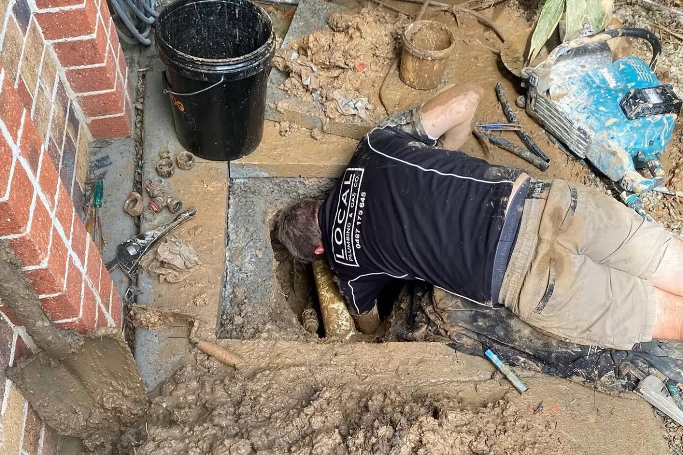 Plumber repairing a burst underground water pipe during excavation on the Gold Coast