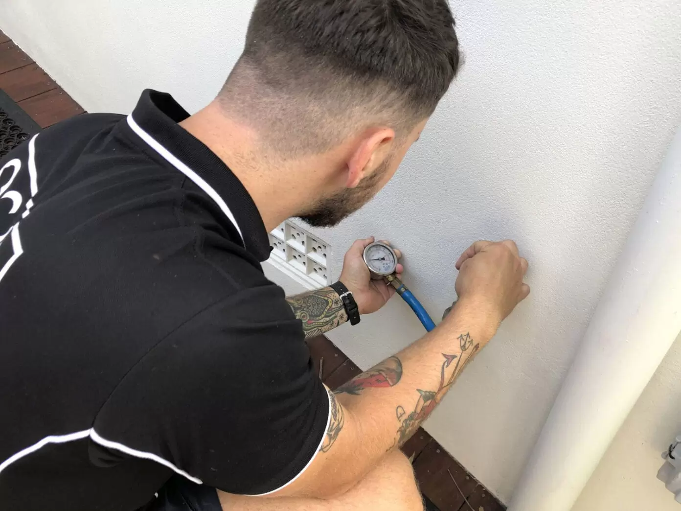 plumber checking home water pressure with gauge on outdoor tap to prevent plumbing leaks