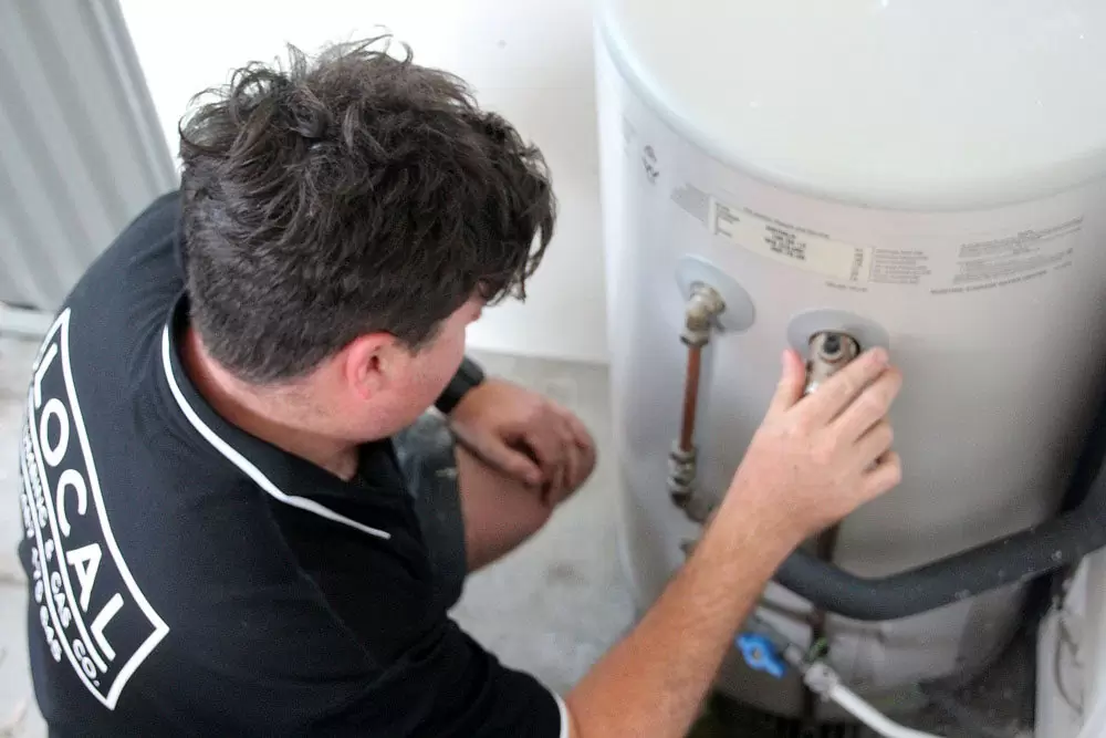 Plumber installing an electric hot water system in a residential home on the Gold Coast