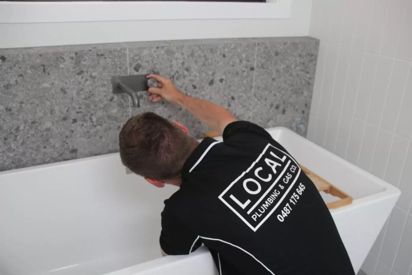 Licensed plumber installing bath tap during bathroom plumbing work on the Gold Coast