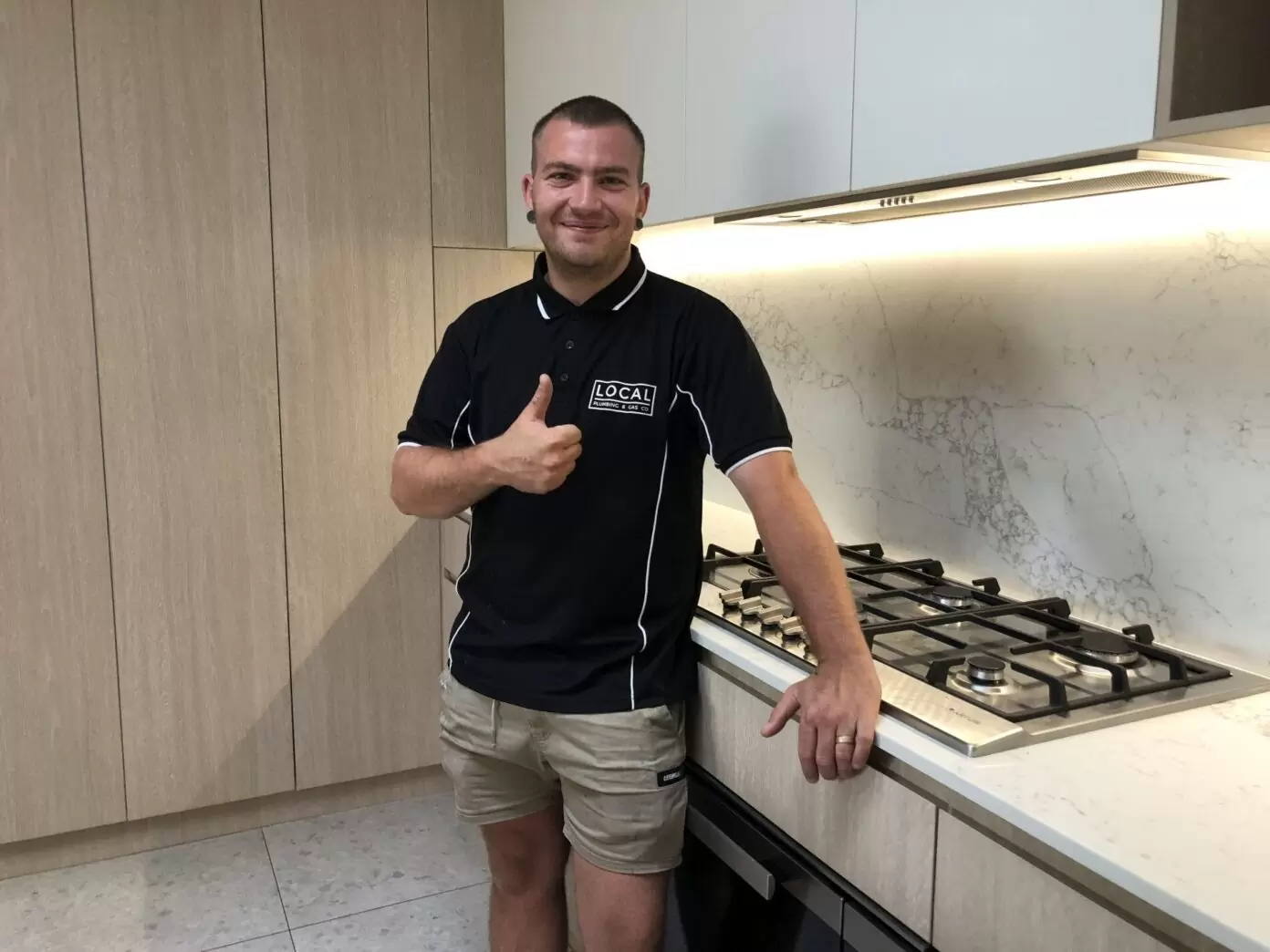 Licensed Gold Coast plumber standing in modern kitchen after completing plumbing work