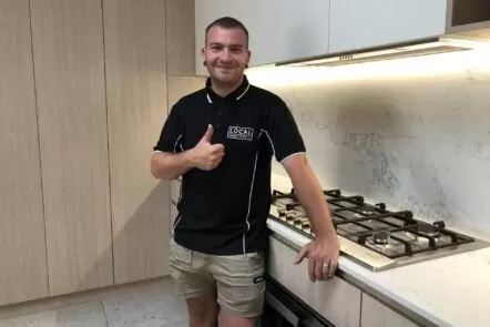 Licensed Gold Coast plumber standing in modern kitchen after completing plumbing work