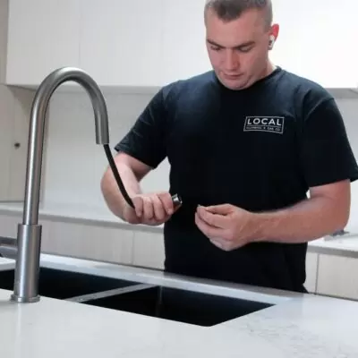 Plumber repairing kitchen sink tap and water flow in a modern Gold Coast kitchen