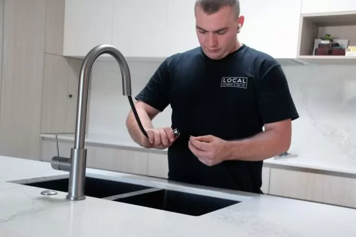 Plumber repairing kitchen sink tap and water flow in a modern Gold Coast kitchen
