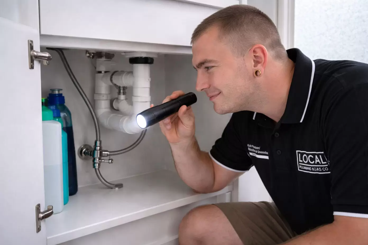 Gold Coast plumber inspecting pipes under bathroom sink during plumbing maintenance inspection