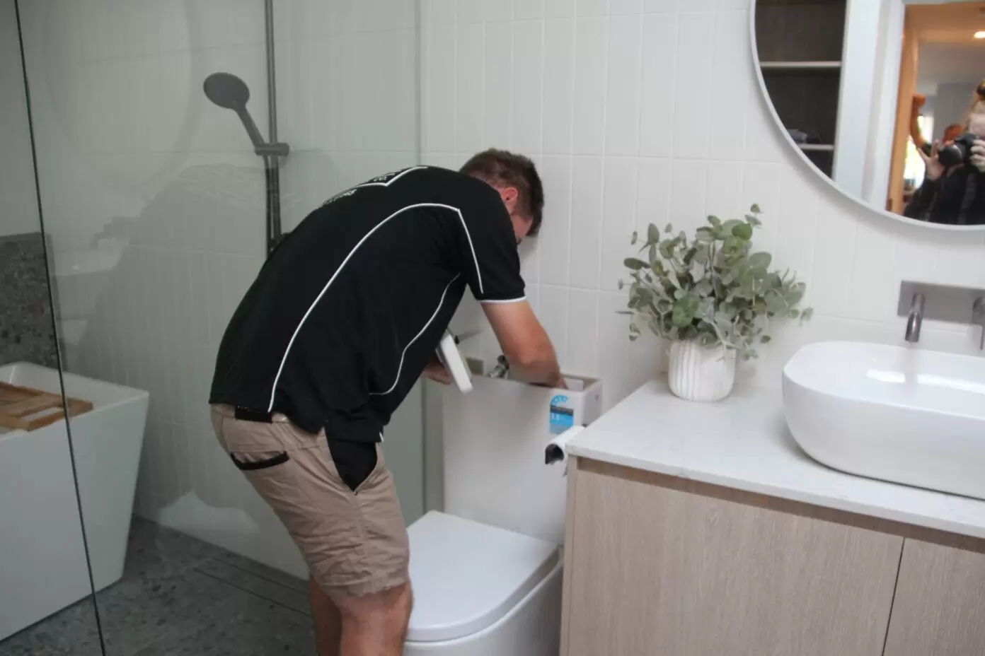 Plumber repairing toilet cistern as part of bathroom plumbing repair on the Gold Coast