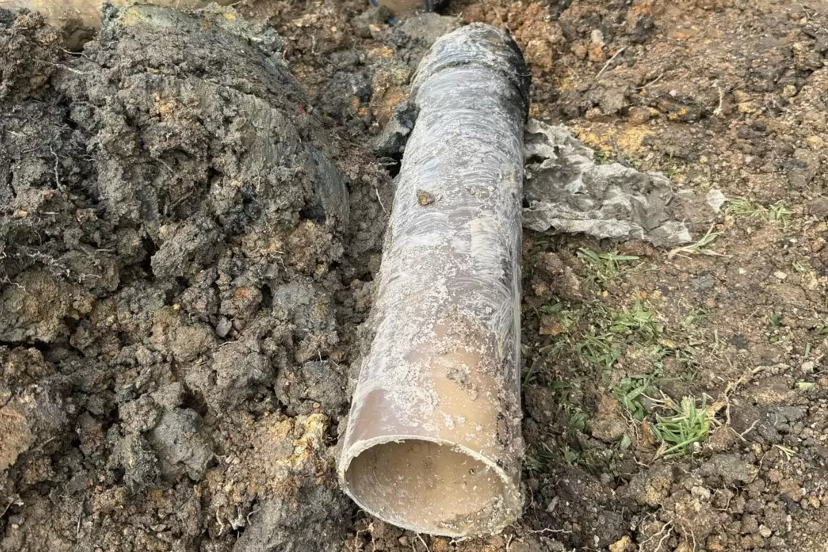 Excavated underground pipe ready for repair beside excavation equipment