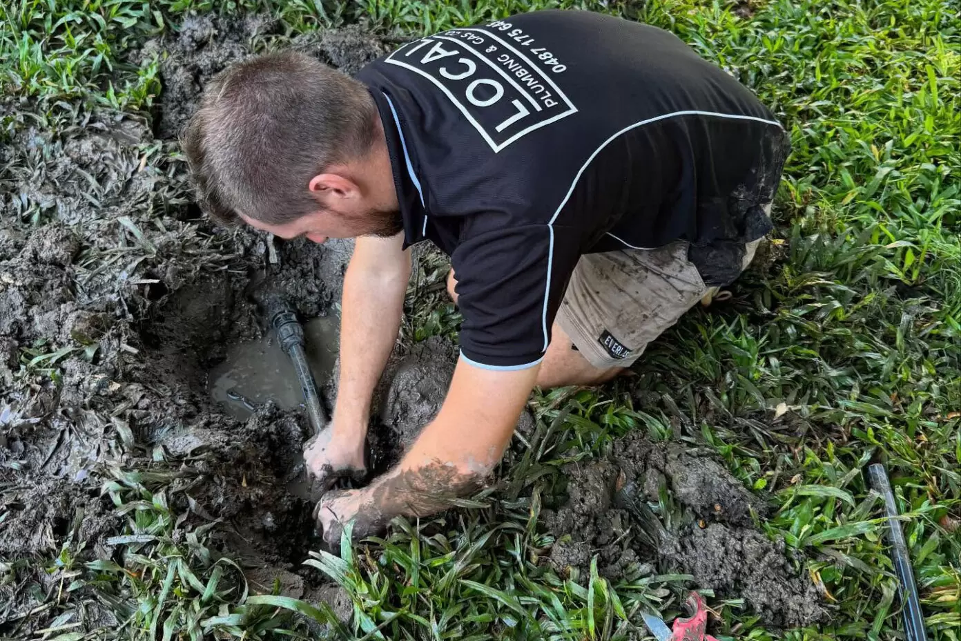 Plumber repairing an underground water pipe beside a house on the Gold Coast