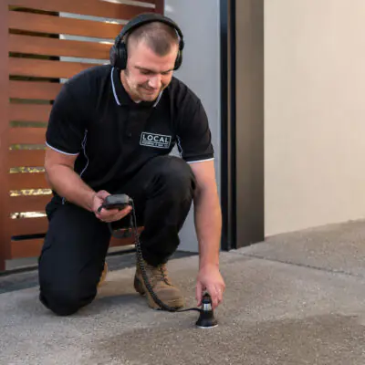 Gold Coast plumber using acoustic leak detection equipment to locate a hidden water leak beneath concrete
