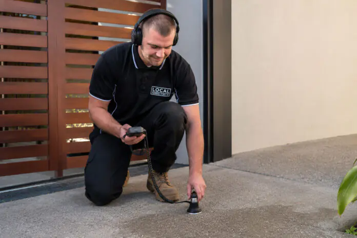 Gold Coast plumber using acoustic leak detection equipment to locate a hidden water leak beneath concrete