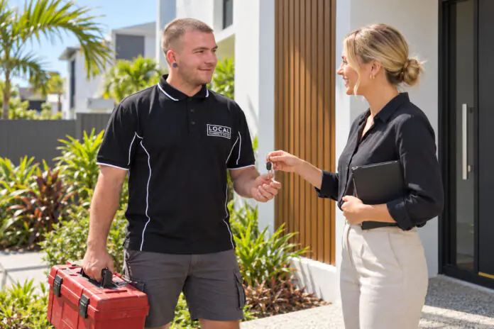 Property manager handing keys to a licensed plumber at a Gold Coast rental townhouse